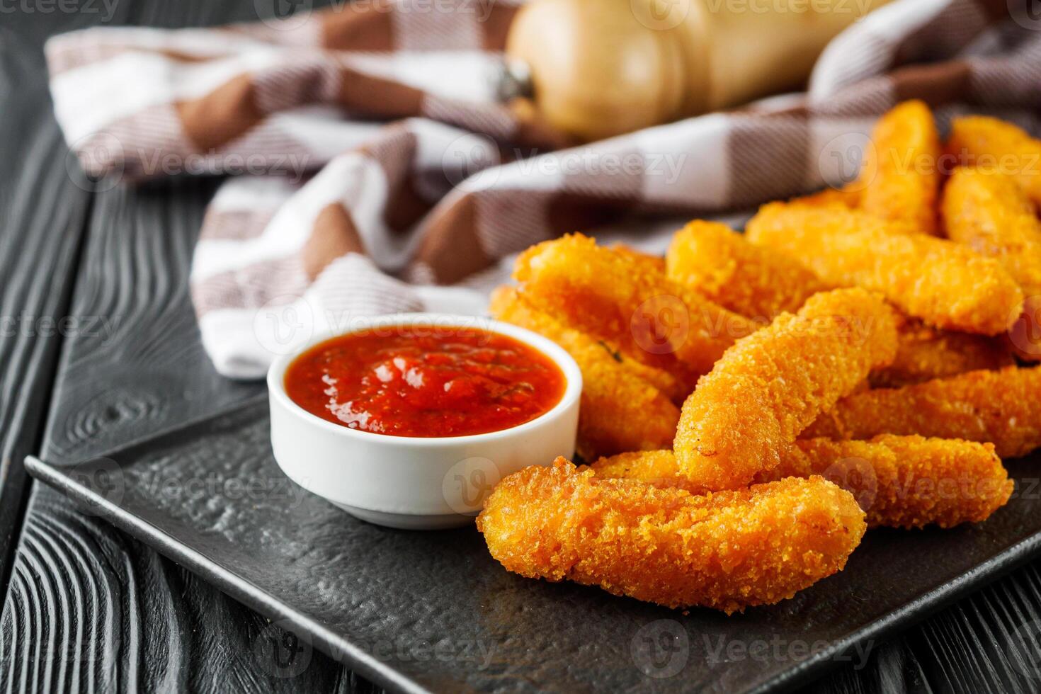 crispy fresh chicken strips on a black rustic wooden background photo