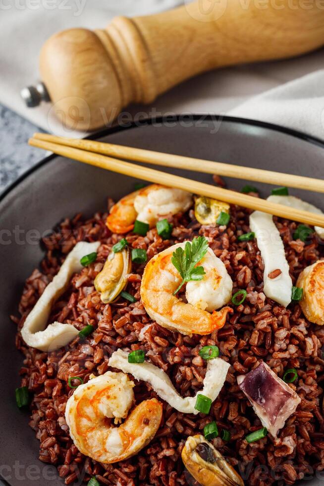 delicious red rice with shrimps and seafood on a gray stone background photo
