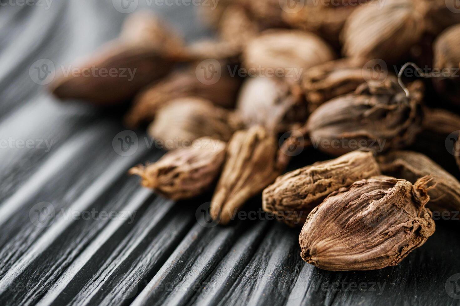 a barrel of dried black cardamom on a black wooden rustic background photo