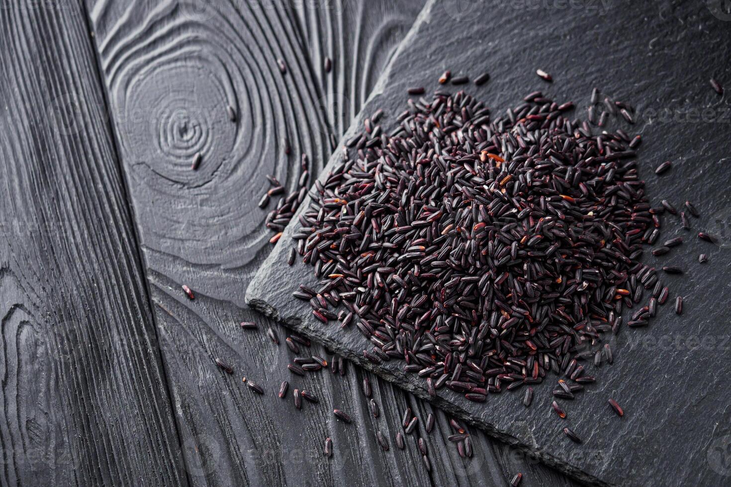raw fresh black rice on black wooden rustic background photo
