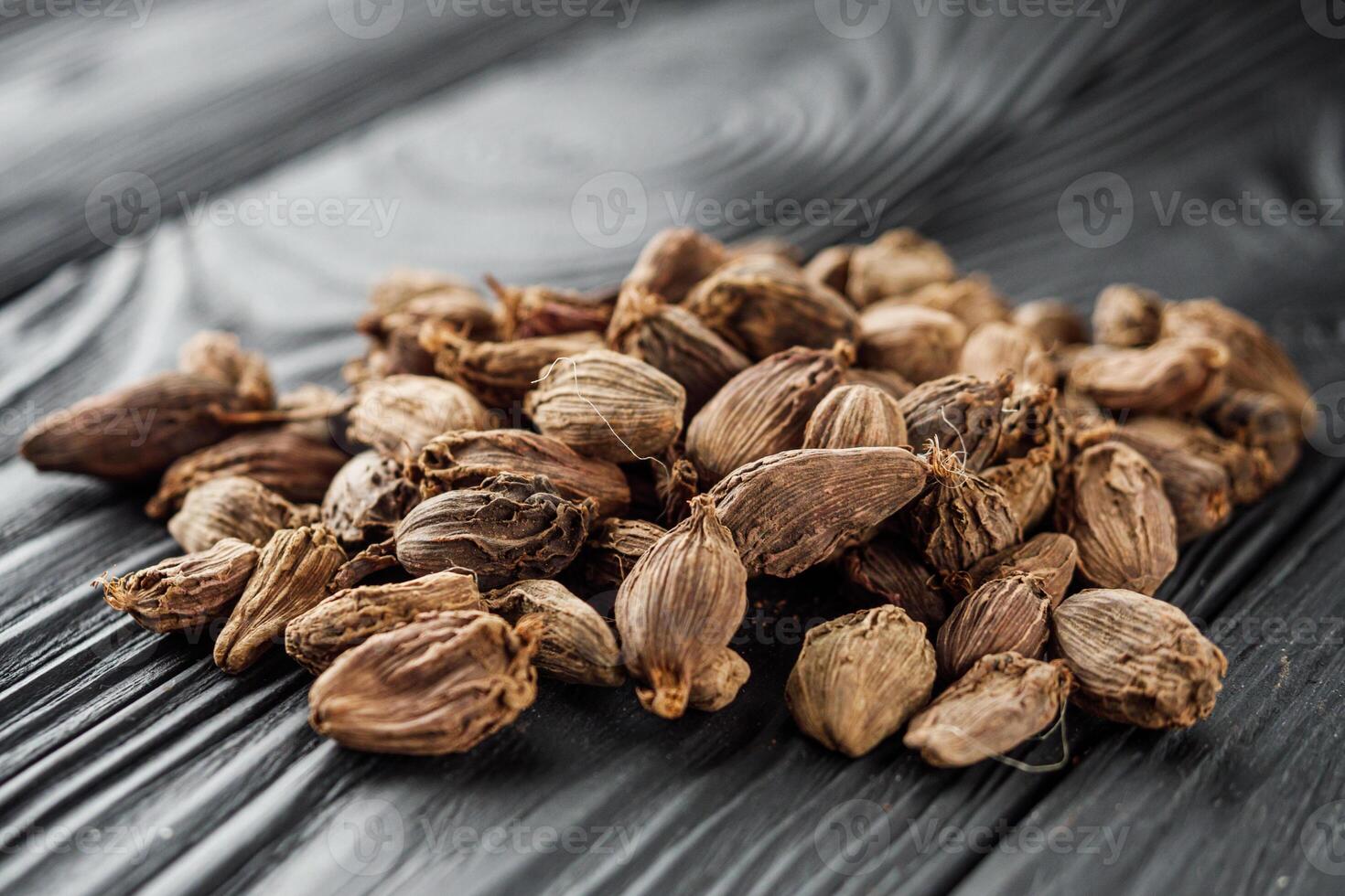 a barrel of dried black cardamom on a black wooden rustic background photo