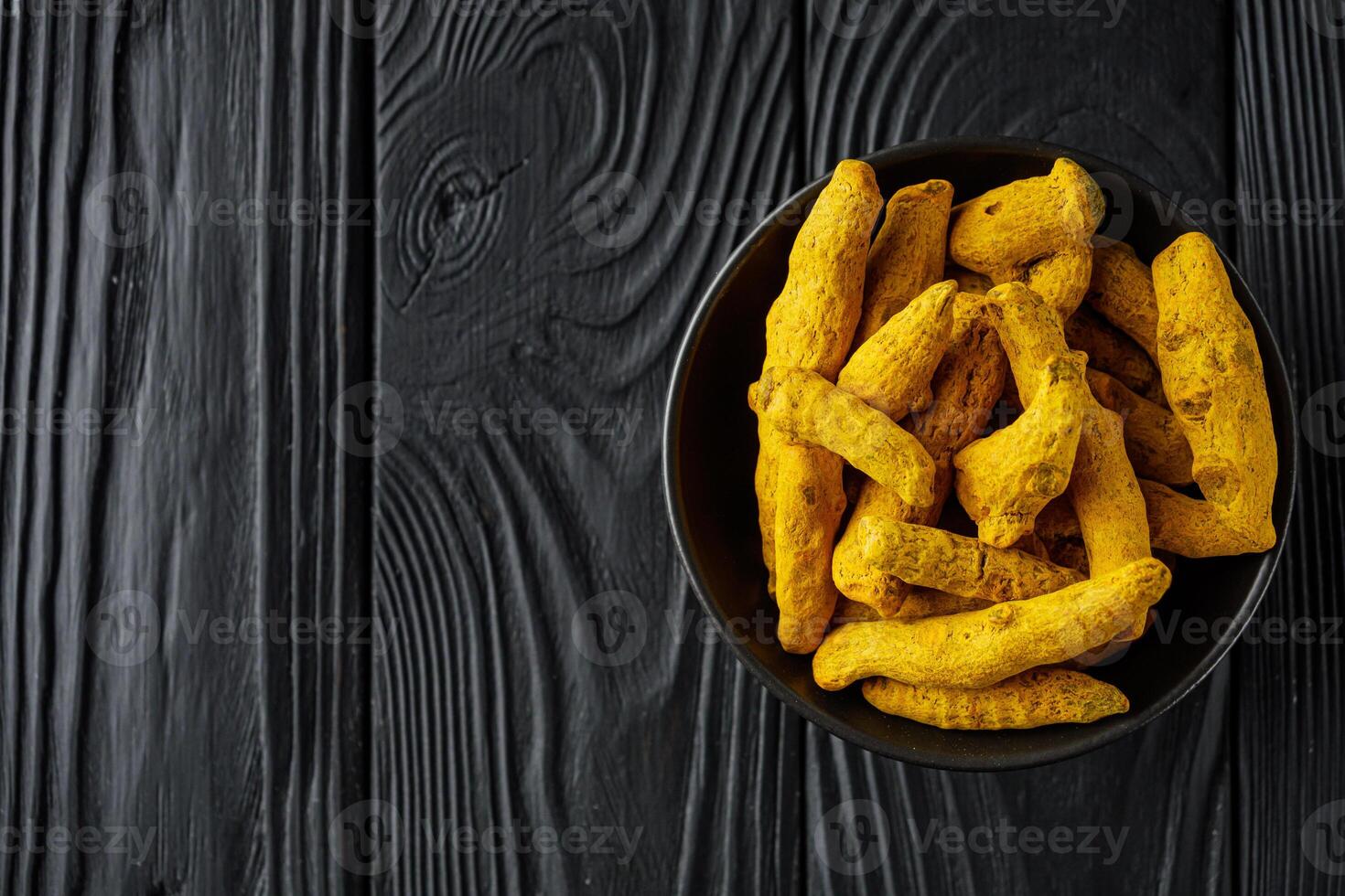 aromatic turmeric root on a black wooden rustic background photo