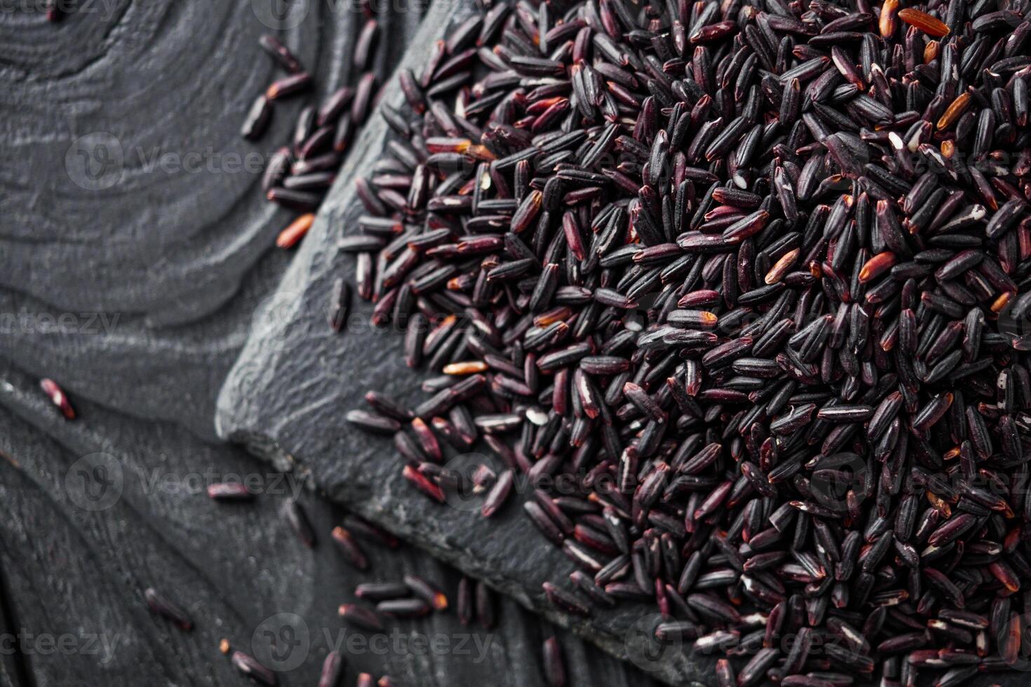 raw fresh black rice on black wooden rustic background photo