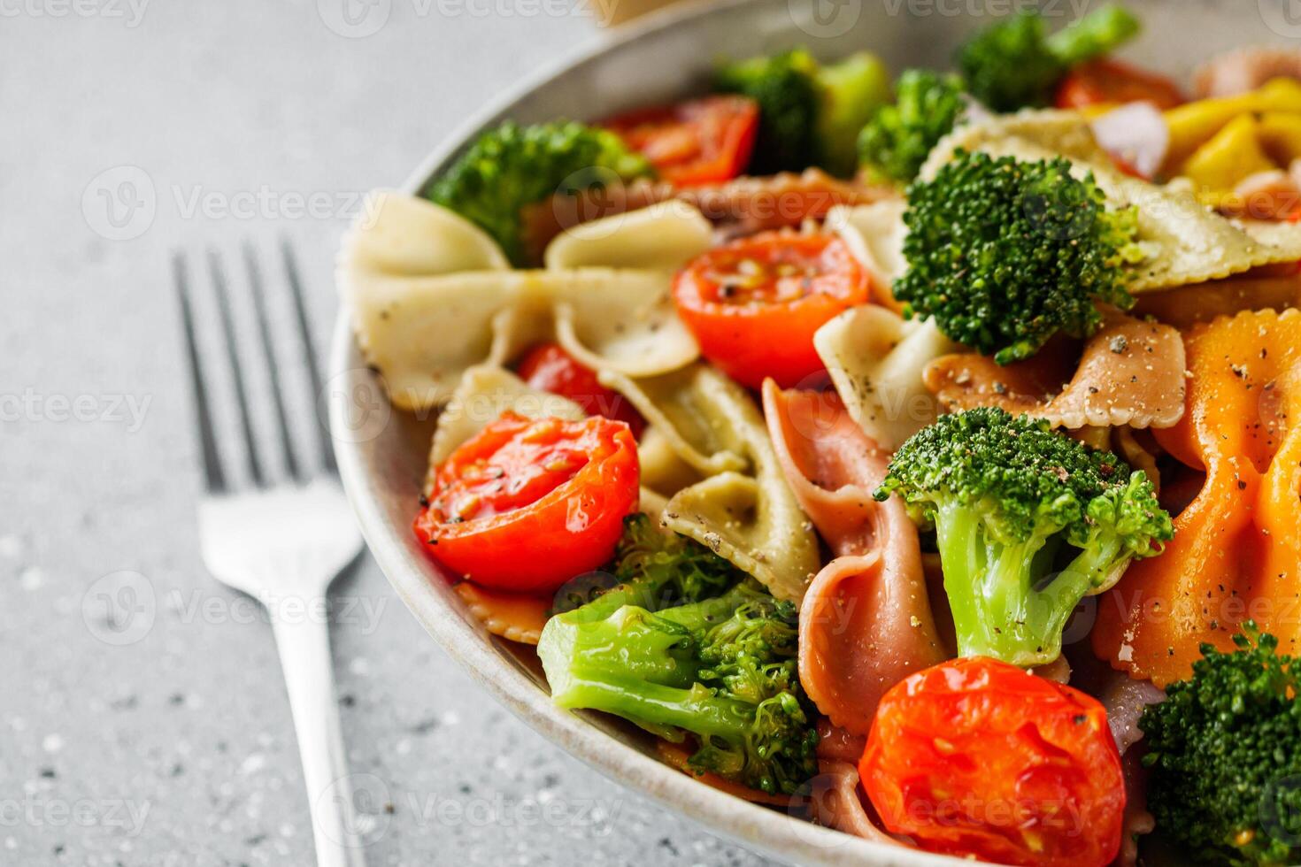 delicious colored farfalle pasta on a stone background photo