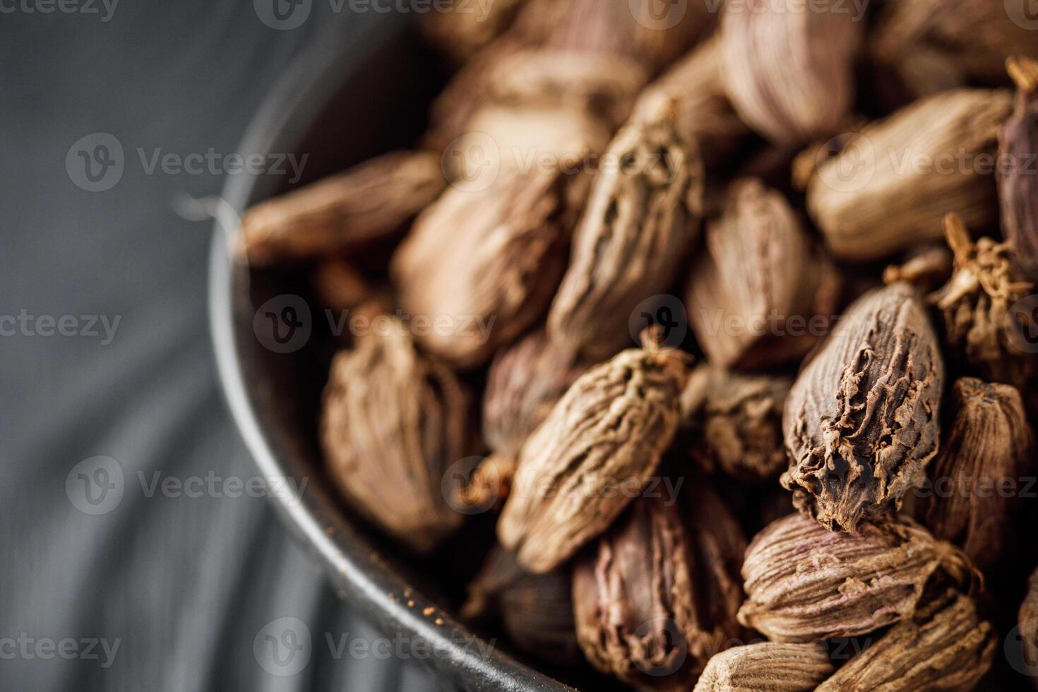 a barrel of dried black cardamom on a black wooden rustic background photo