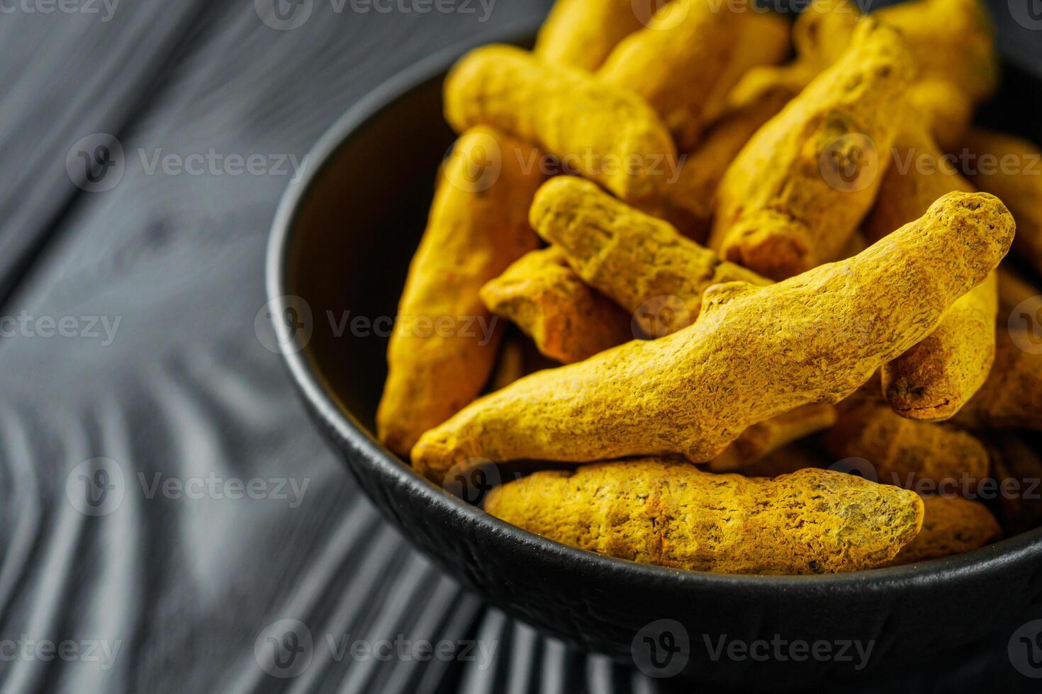 aromatic turmeric root on a black wooden rustic background photo