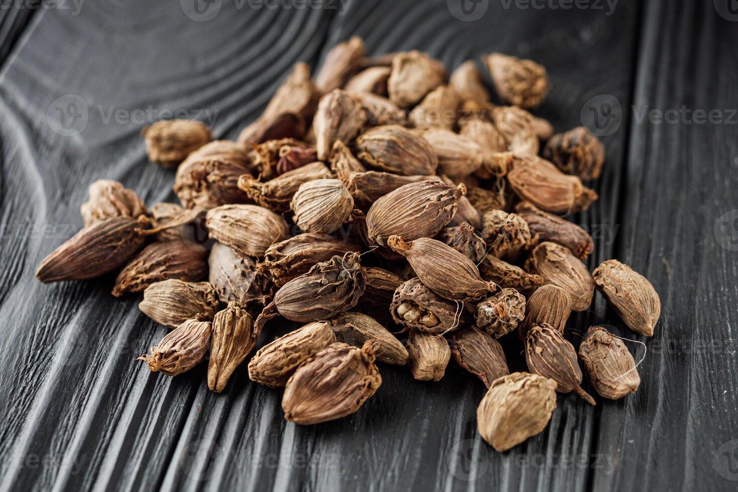a barrel of dried black cardamom on a black wooden rustic background photo