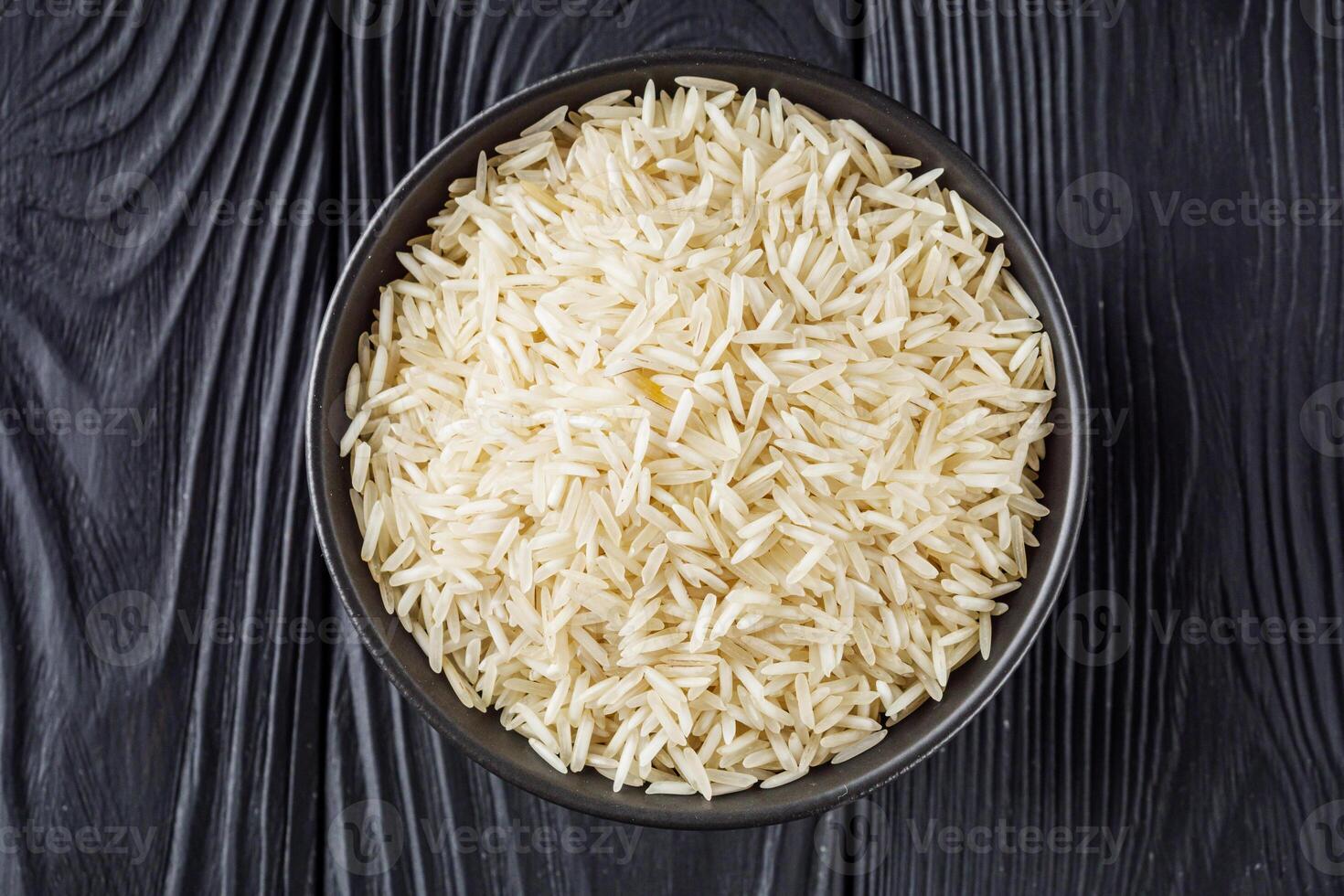 raw basmati rice on a black wooden background photo