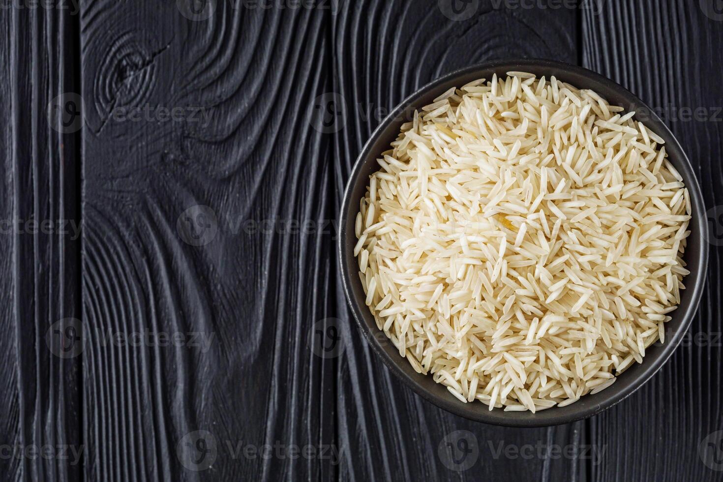 raw basmati rice on a black wooden background photo