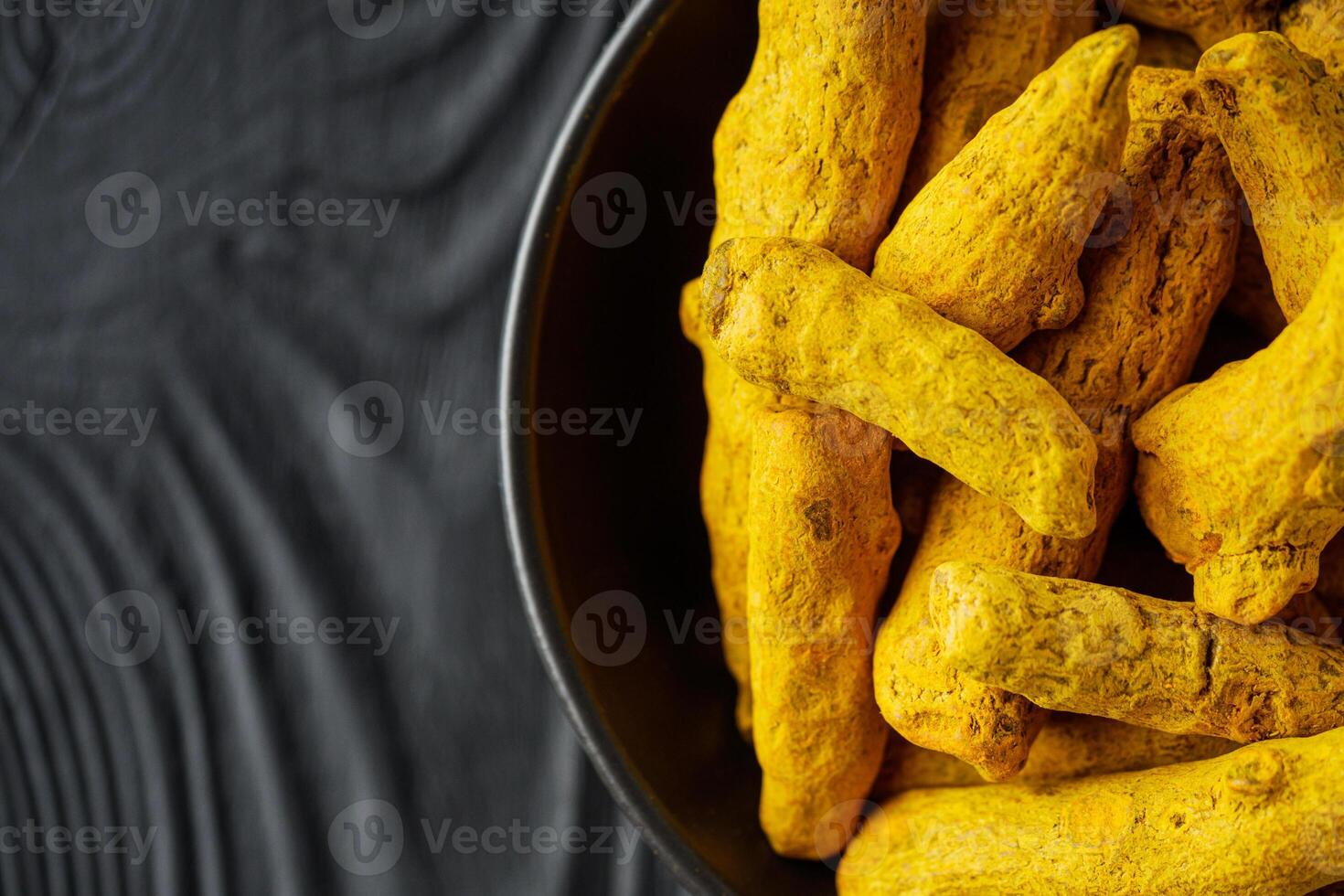 aromatic turmeric root on a black wooden rustic background photo