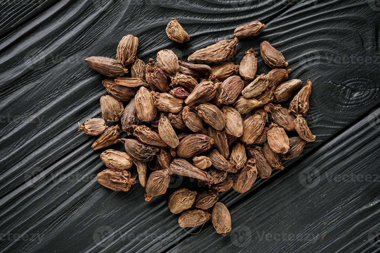 a barrel of dried black cardamom on a black wooden rustic background photo
