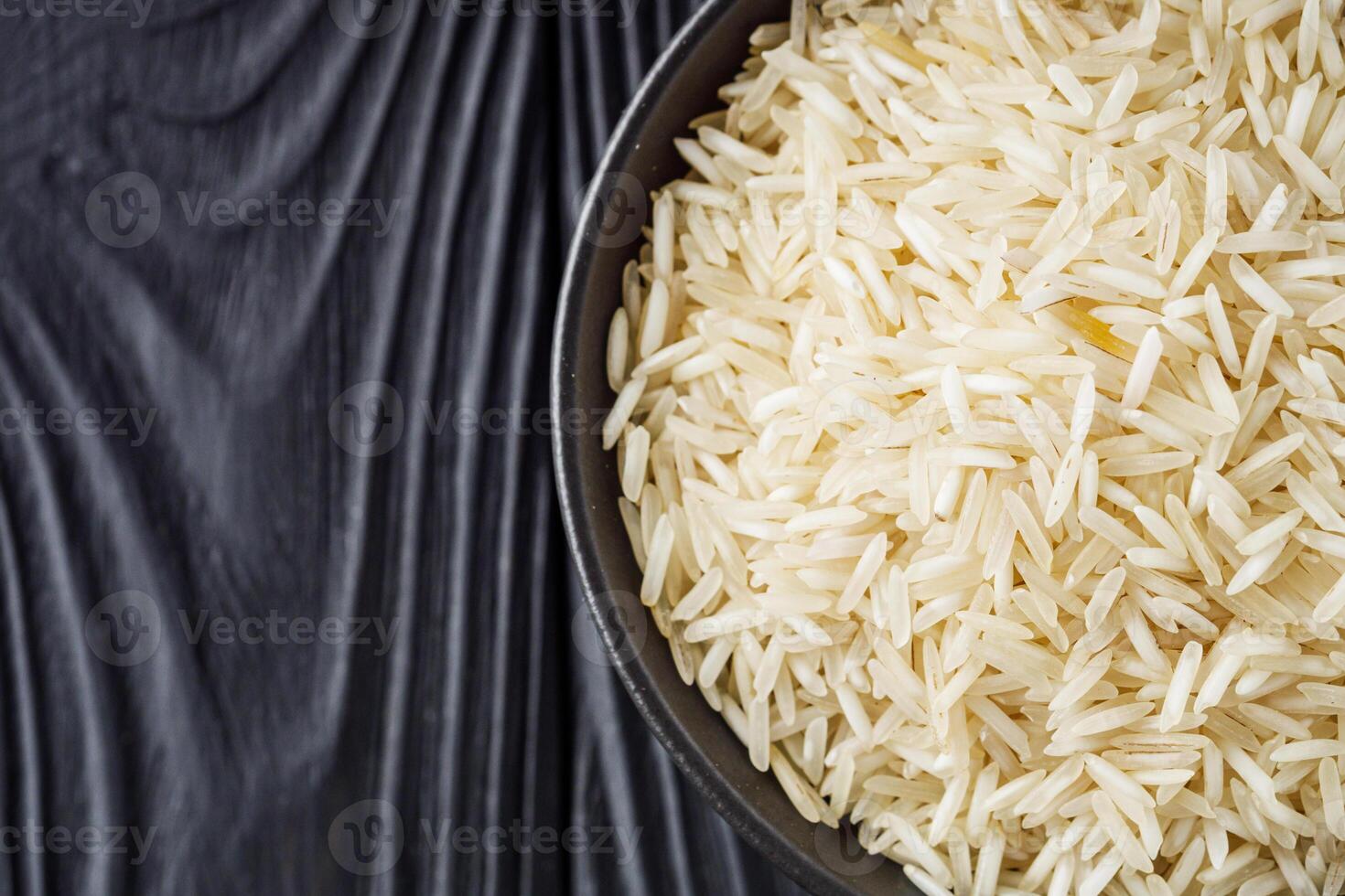 raw basmati rice on a black wooden background photo