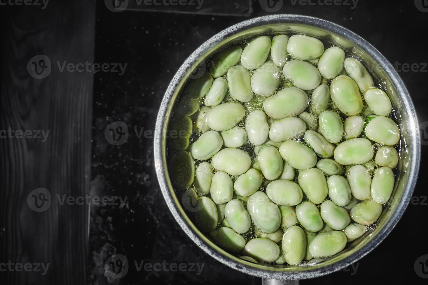 fresh greens broad beans fava boiled on a dark background photo