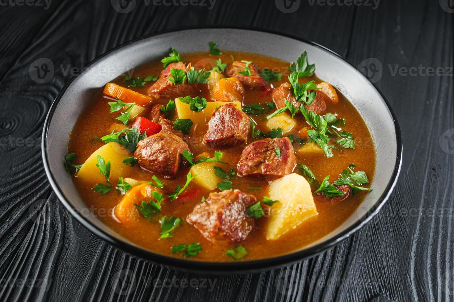 fragrant thick goulash soup on a black wooden rustic background photo