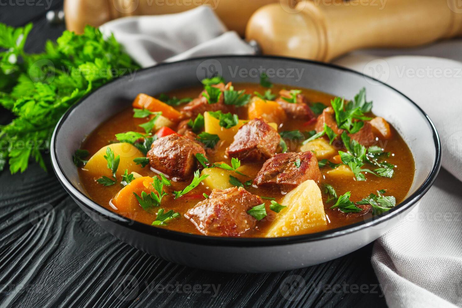 fragrant thick goulash soup on a black wooden rustic background photo