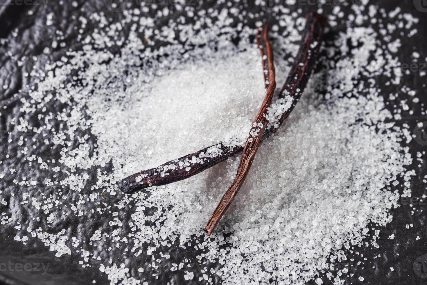 snow-white aromatic vanilla sugar on a black background photo