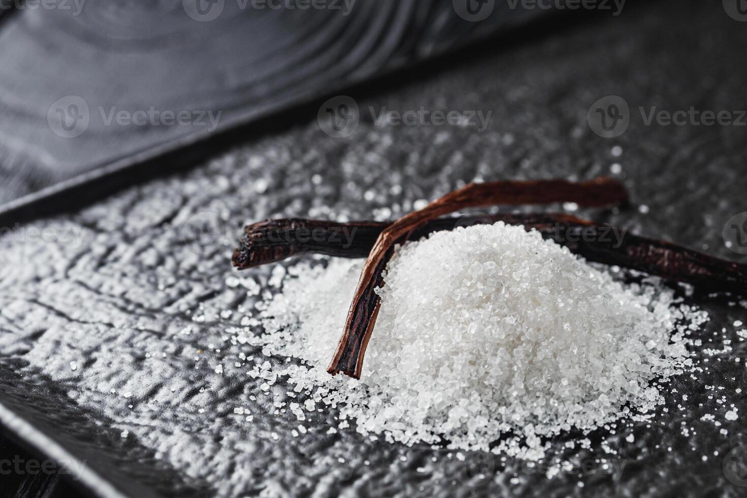 snow-white aromatic vanilla sugar on a black background photo