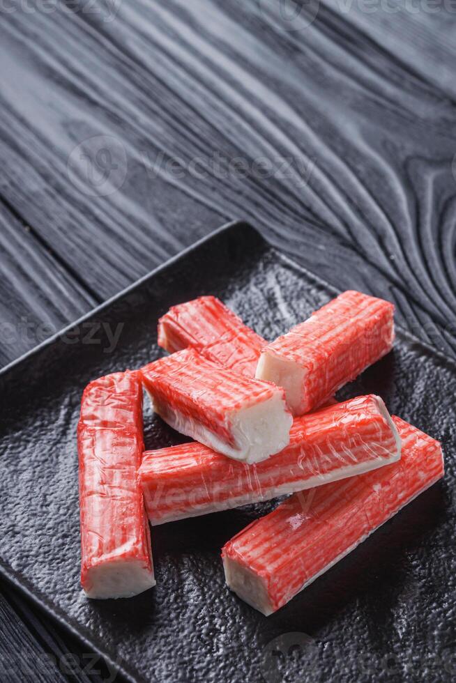 fresh chilled surimi crab sticks on black wooden background photo