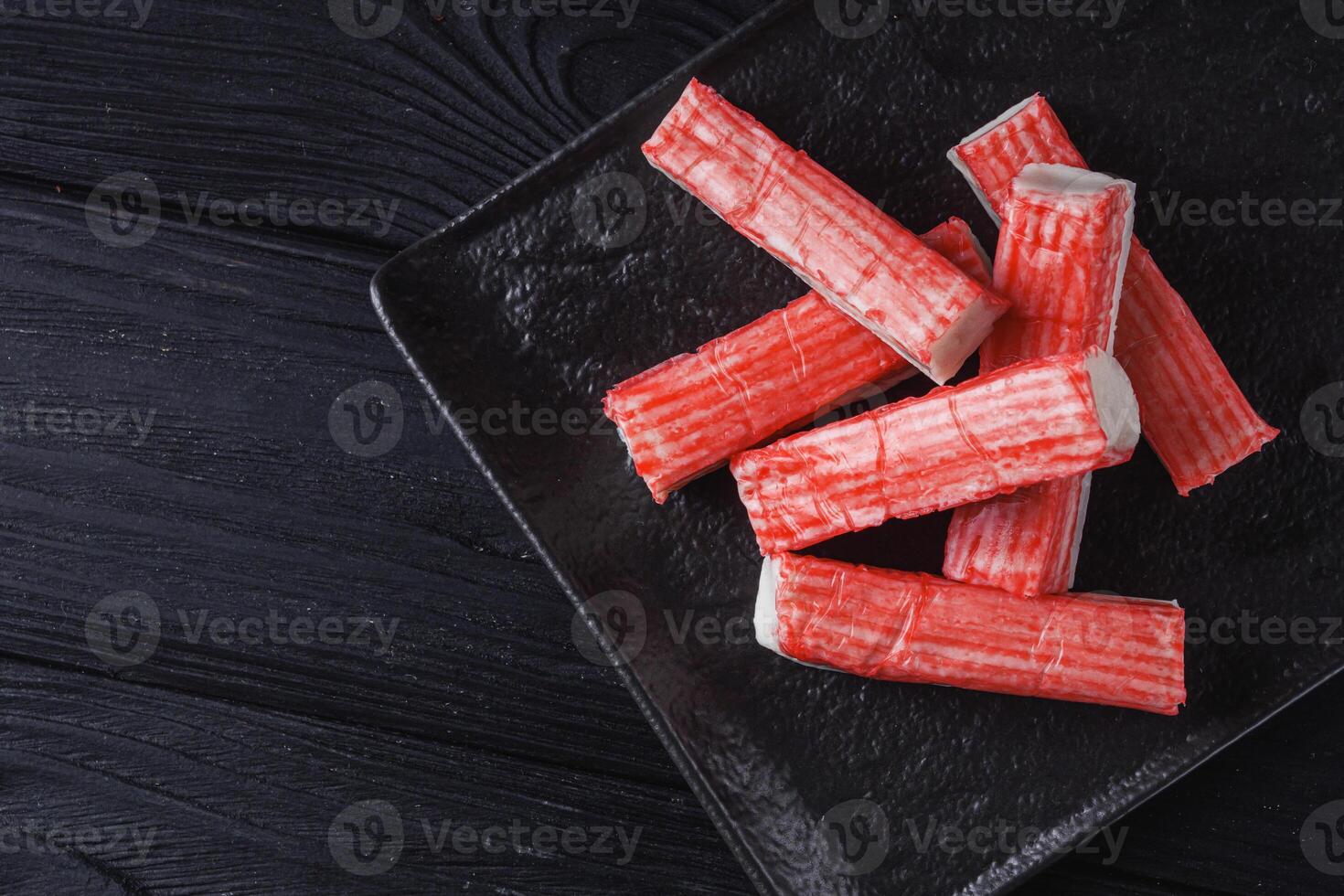 fresh chilled surimi crab sticks on black wooden background photo