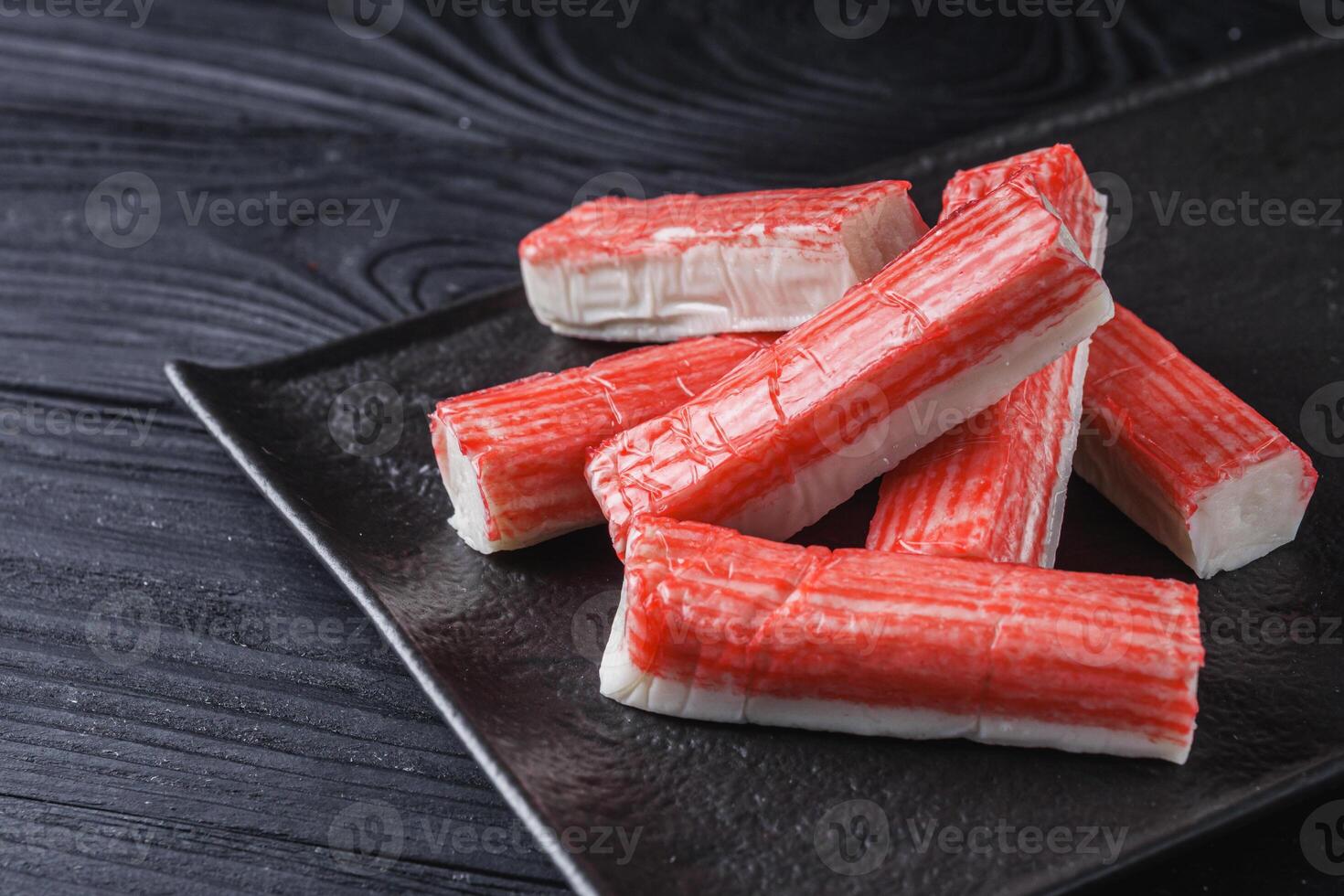 fresh chilled surimi crab sticks on black wooden background photo