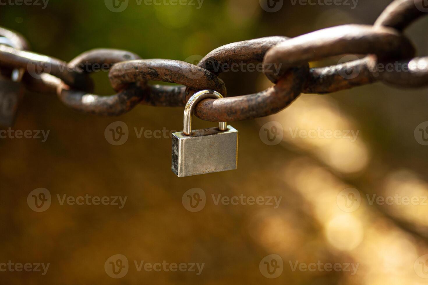 Small padlock on a large vintage chain. A symbol of strong love. Bokeh and blurred back photo