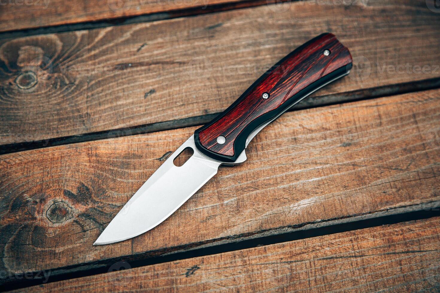 Folding pocket knife with wooden handle. A small knife on a wooden surface. photo