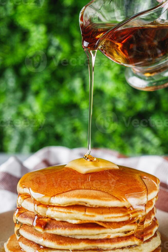 fresh tasty pancakes with maple syrup on a light stone background photo