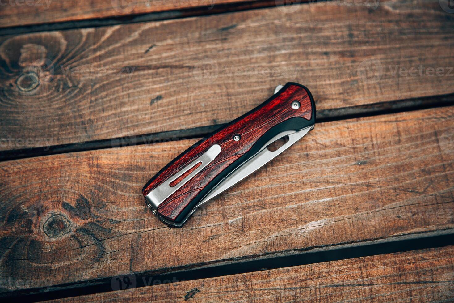 Folding pocket knife with wooden handle. A small knife on a wooden surface. photo