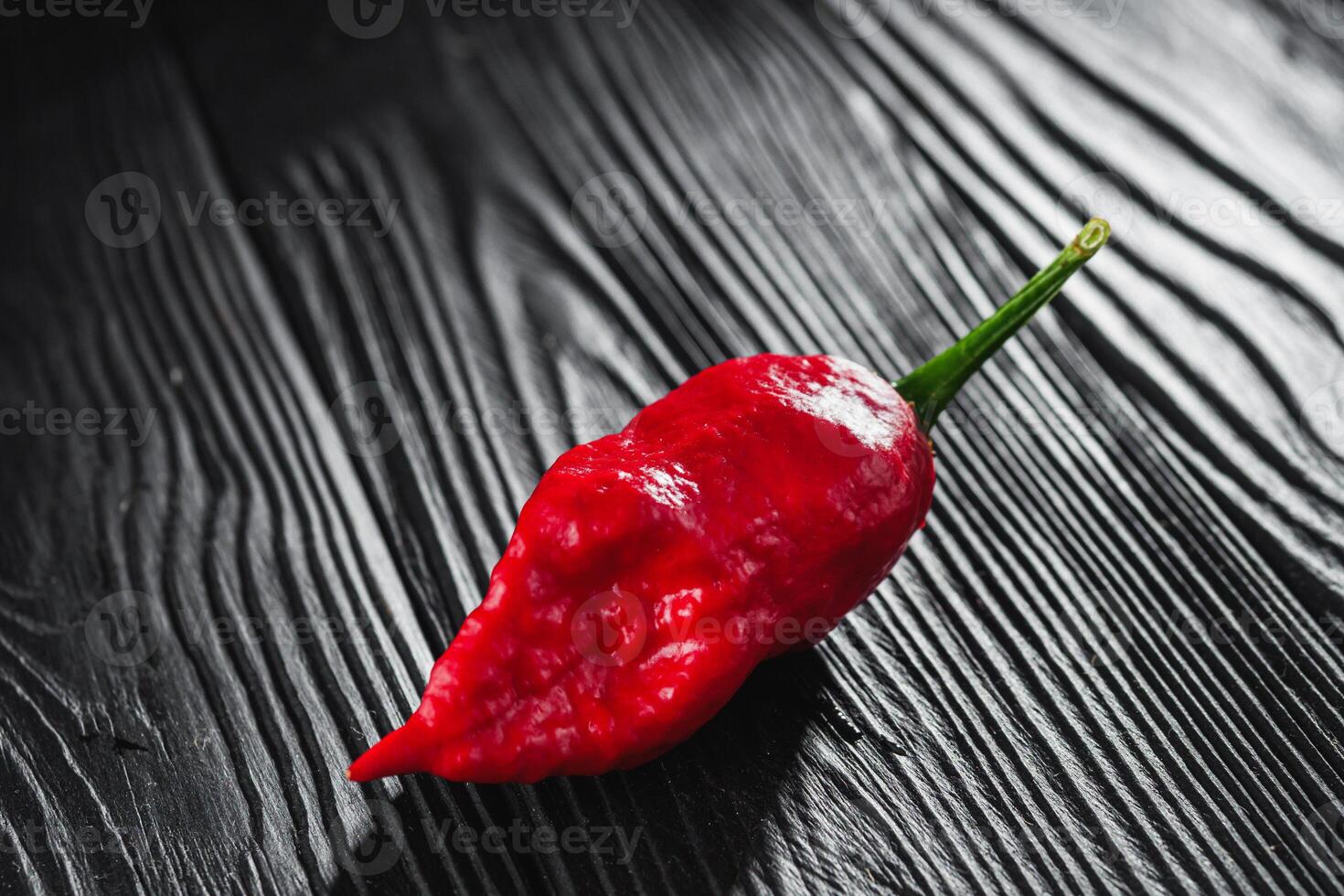 fresh red extra hot bhut jholokiya pepper on black wooden rustic background photo