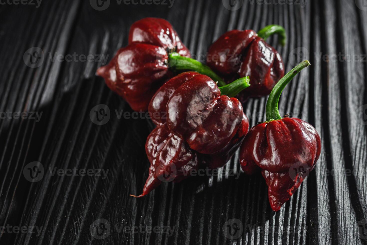 fresh brown extra hot carolina reaper chocolate pepper on black wooden rustic background photo
