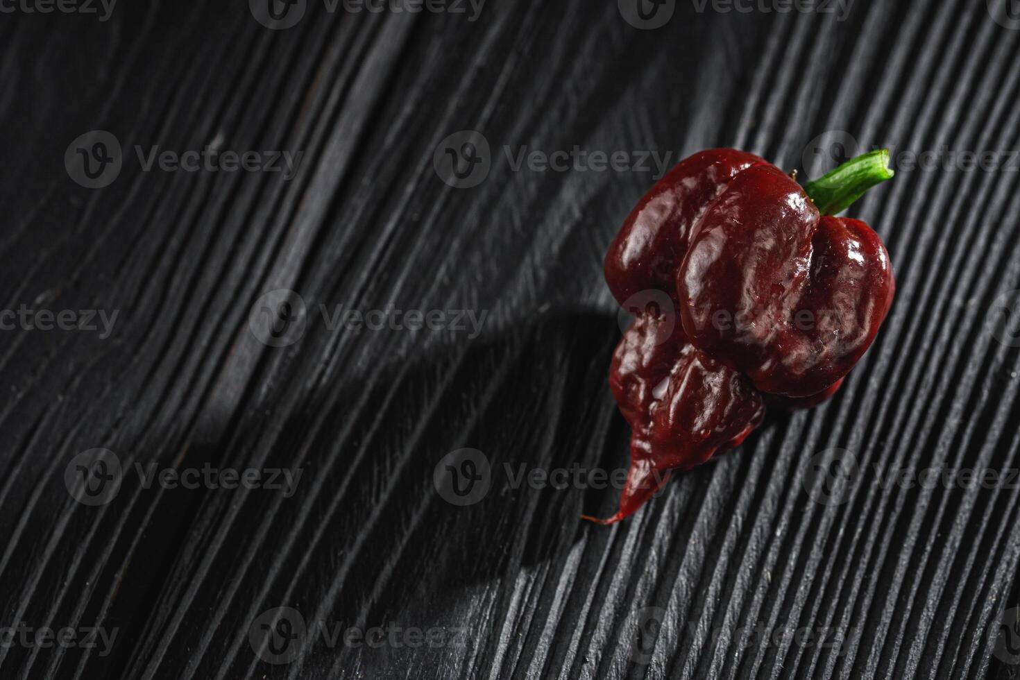 fresh brown extra hot carolina reaper chocolate pepper on black wooden rustic background photo