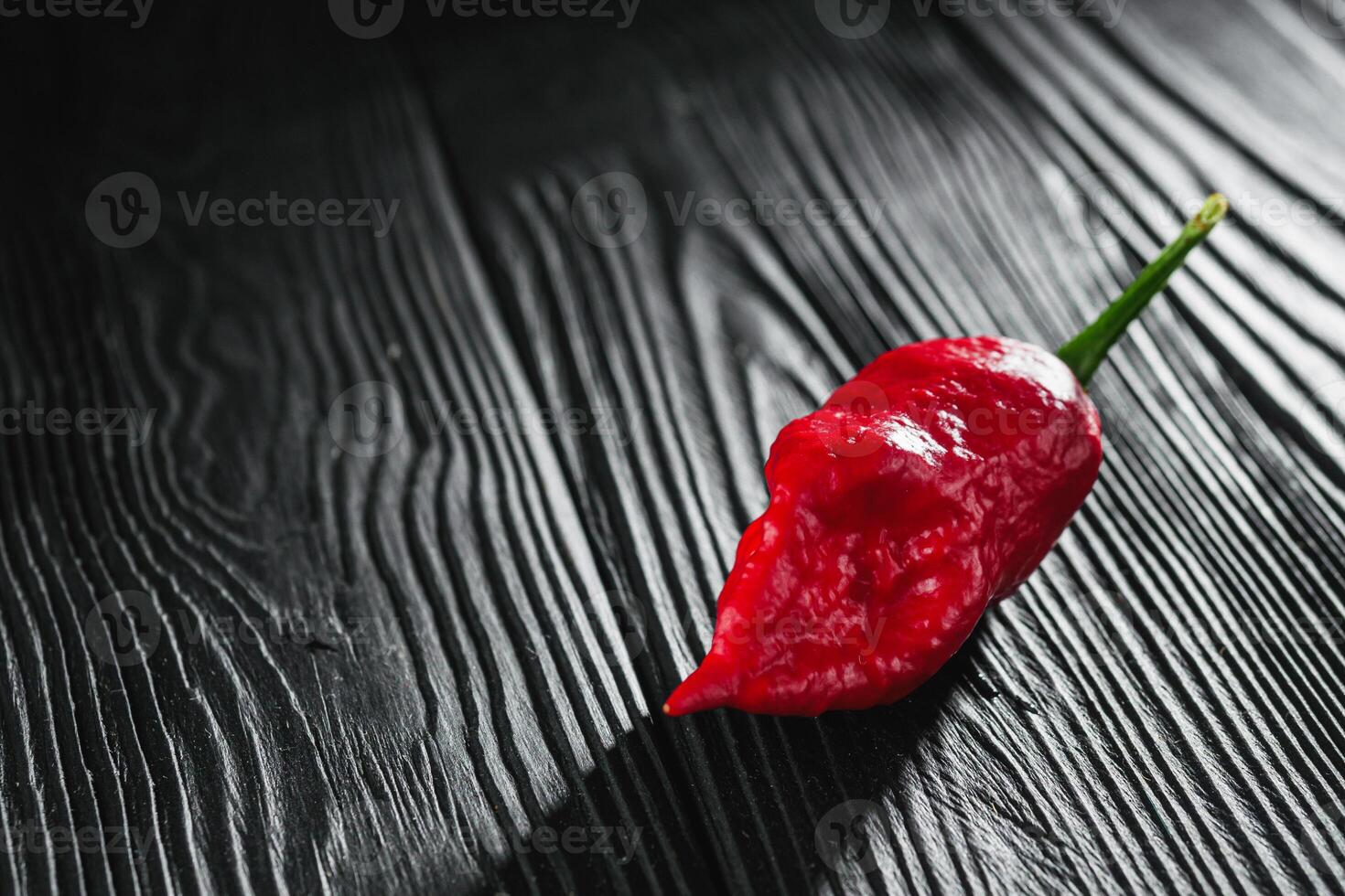 fresh red extra hot bhut jholokiya pepper on black wooden rustic background photo