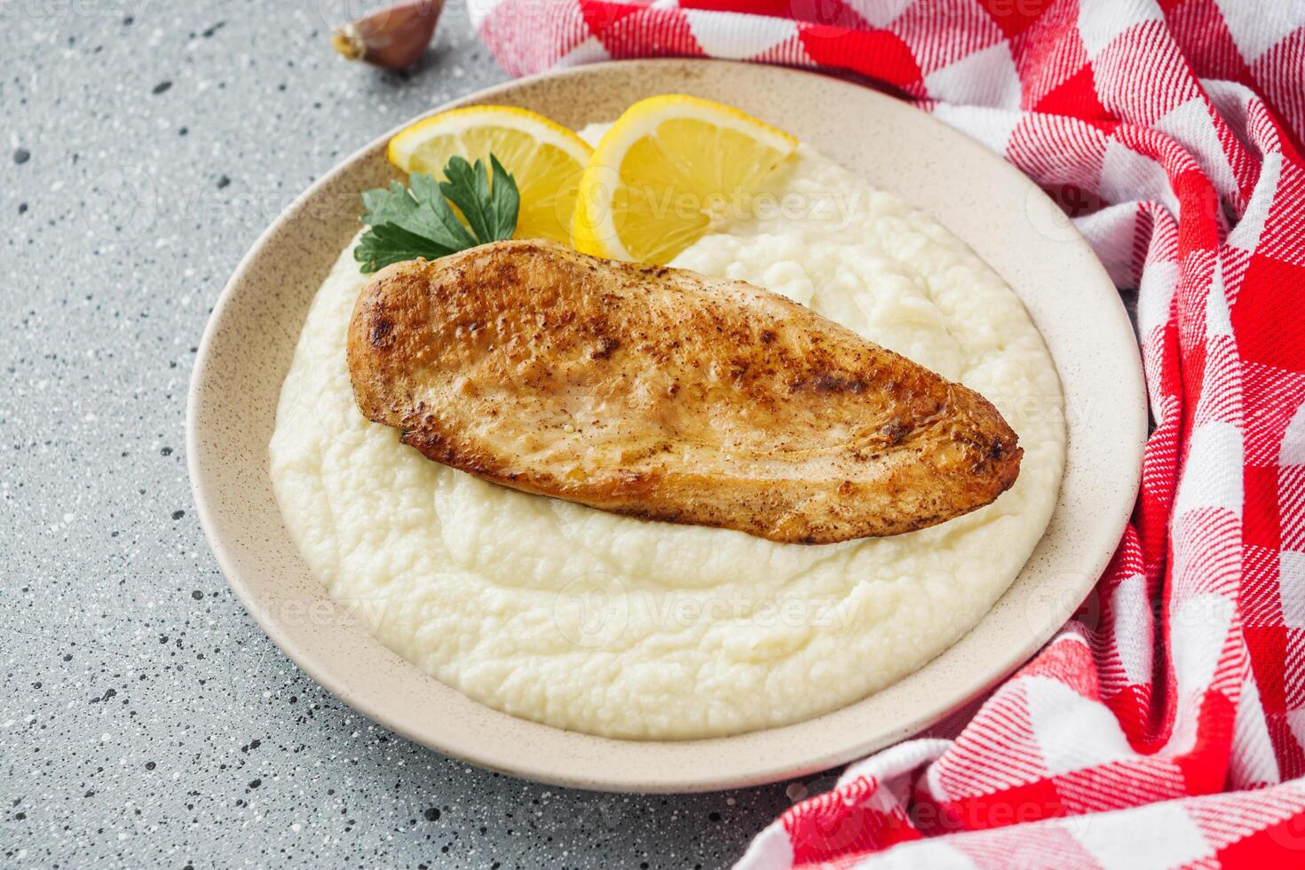 delicious mashed cauliflower and fried chicken breast on a light stone background photo