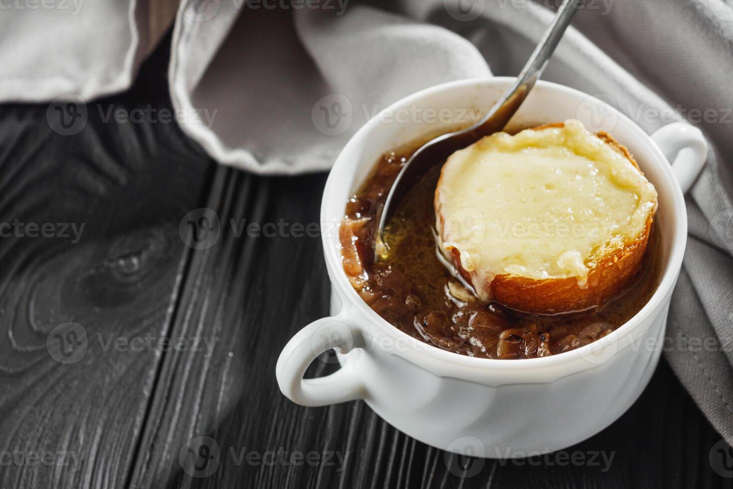 delicious original french onion soup on a black rustic wooden background photo