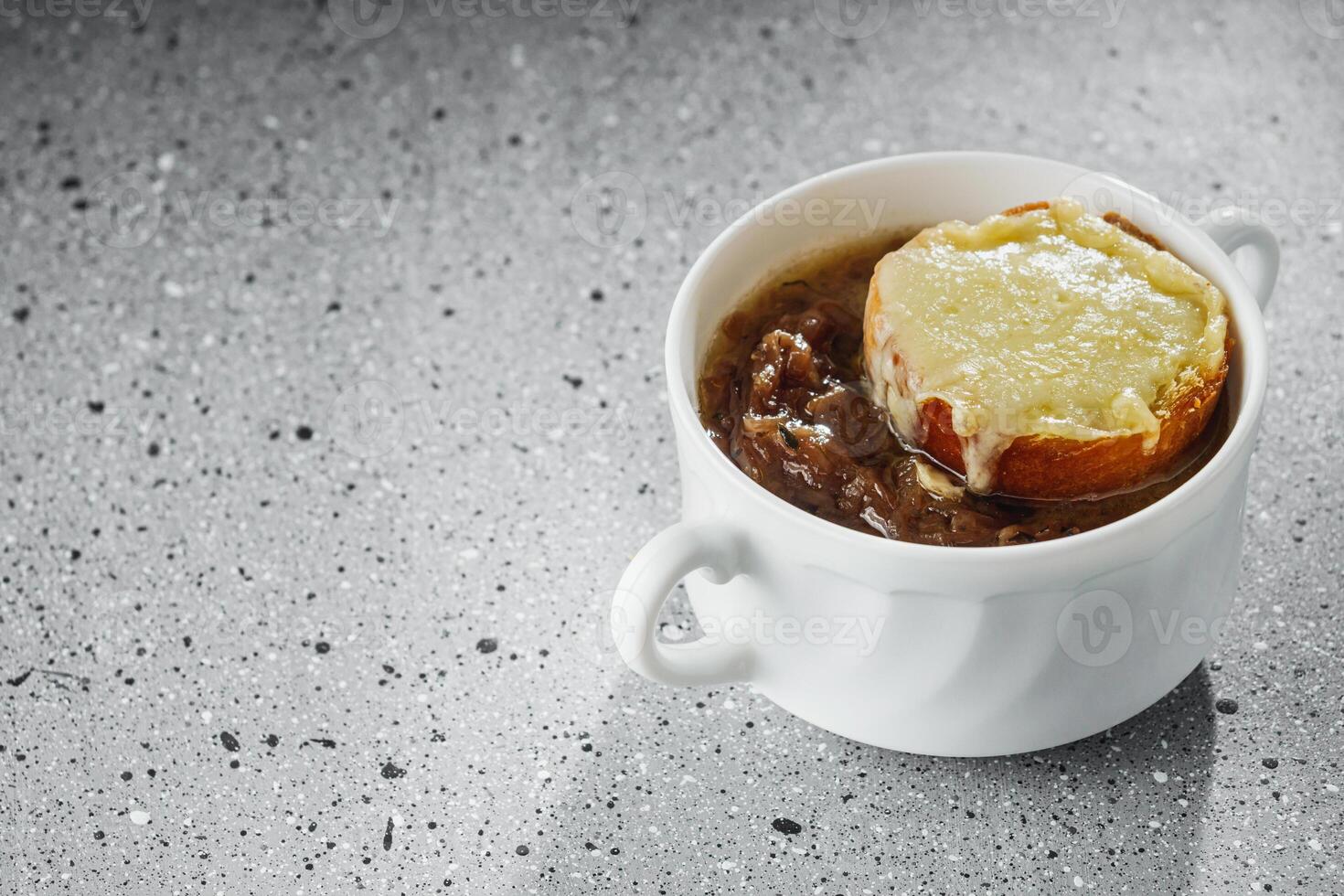 delicious original French onion soup on a light stone background photo