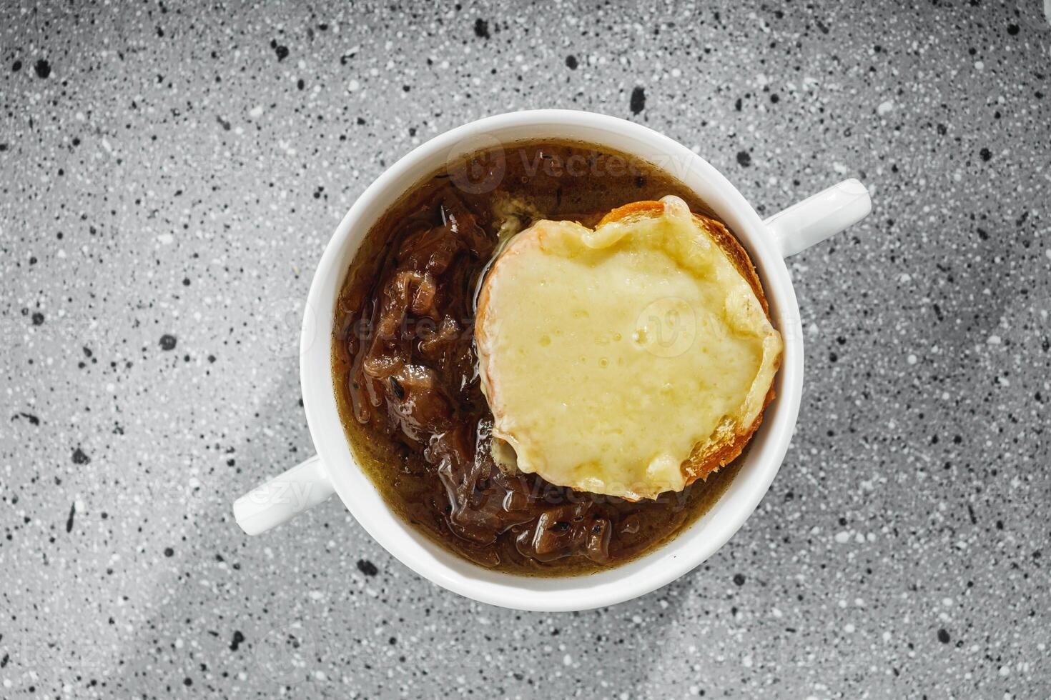 delicious original French onion soup on a light stone background photo