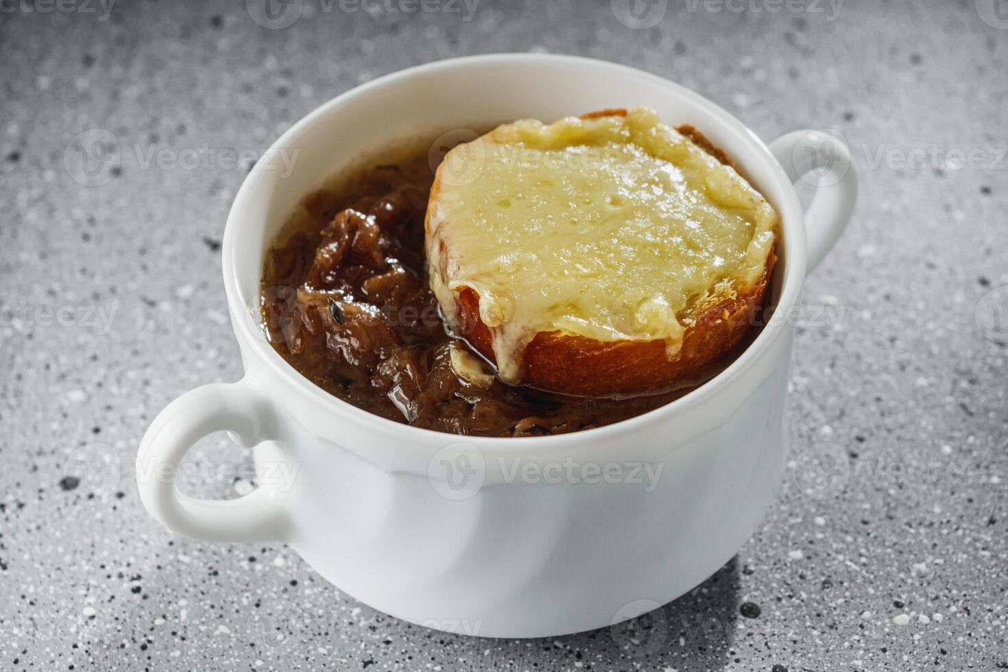 delicious original French onion soup on a light stone background photo