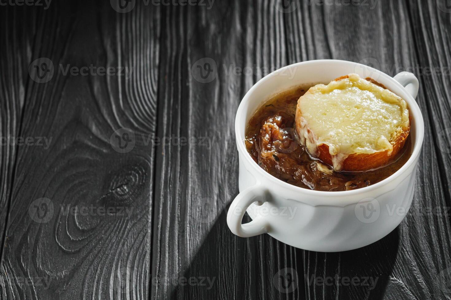 delicious original french onion soup on a black rustic wooden background photo