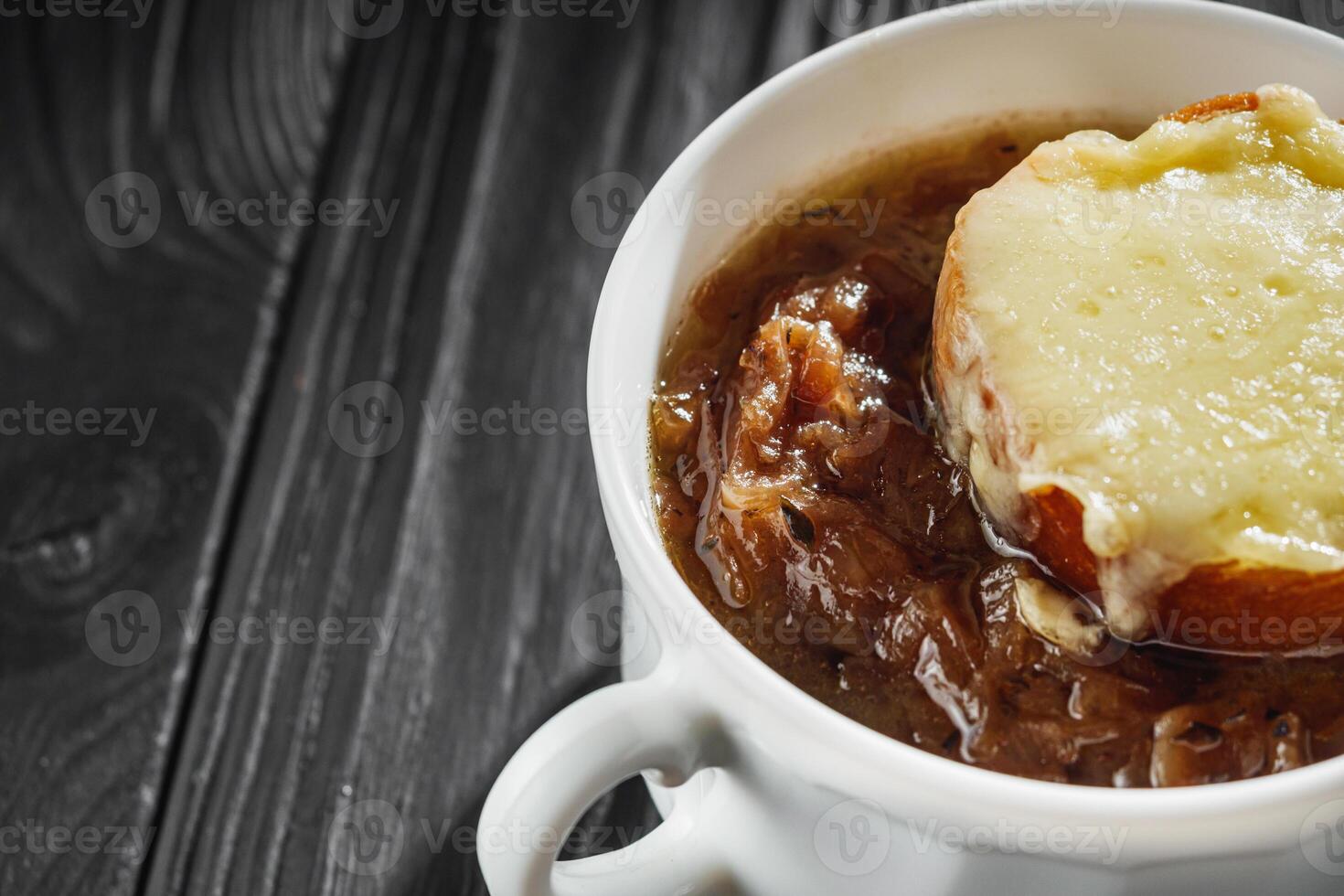 delicious original french onion soup on a black rustic wooden background photo