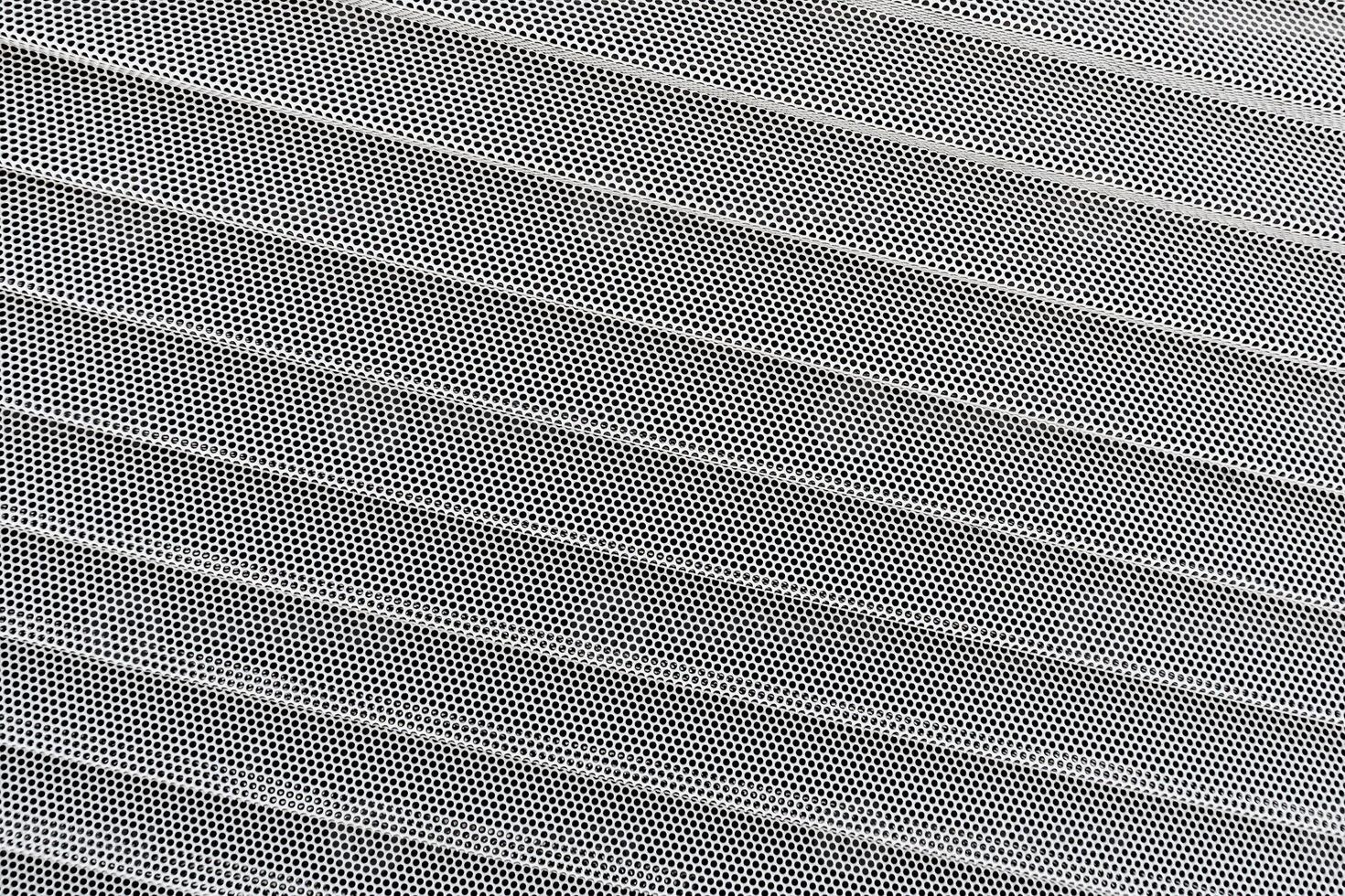 Background of wavy metallic grid with holes. Metal mesh as back. Perforated metal back. photo