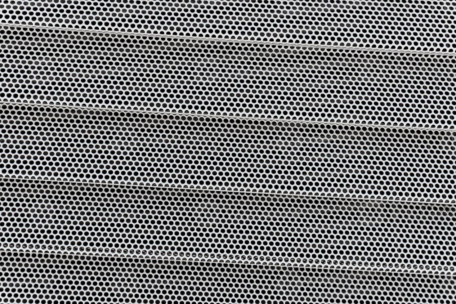 Background of wavy metallic grid with holes. Metal mesh as back. Perforated metal back. photo