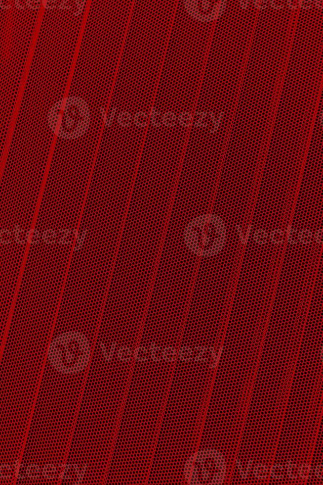 Red background of wavy metallic grid with holes. Metal mesh as back. Perforated metal. photo