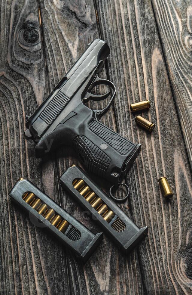 Pistol and cartridges for it on a wooden background. A short-barreled weapon for self-defense photo