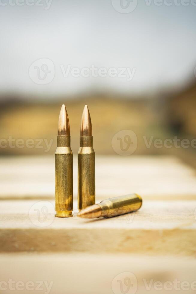 308 caliber ammunition for a rifle standing on a wooden table on the background of the shooting range photo