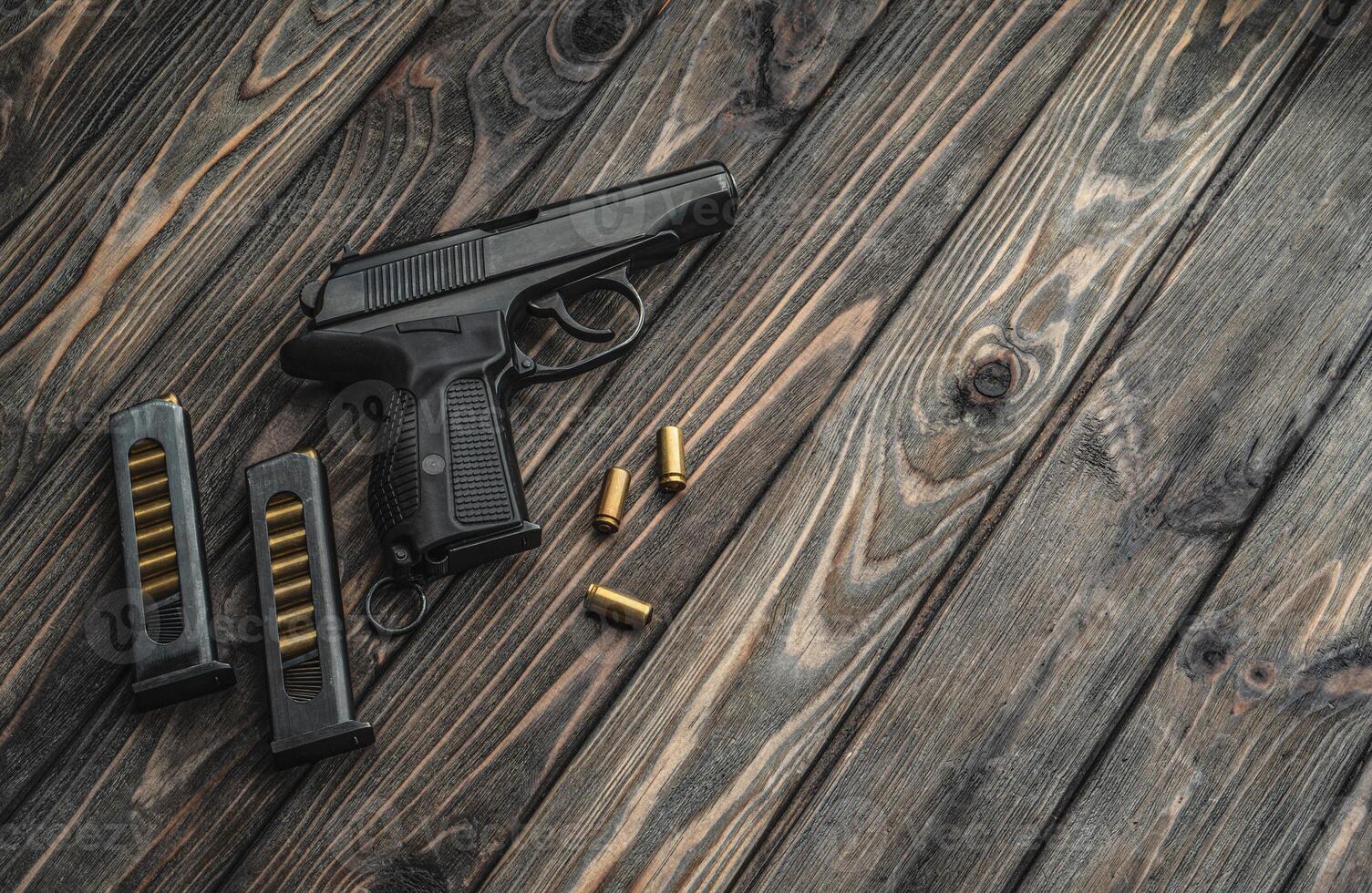 Pistol and cartridges for it on a wooden background. A short-barreled weapon for self-defense photo