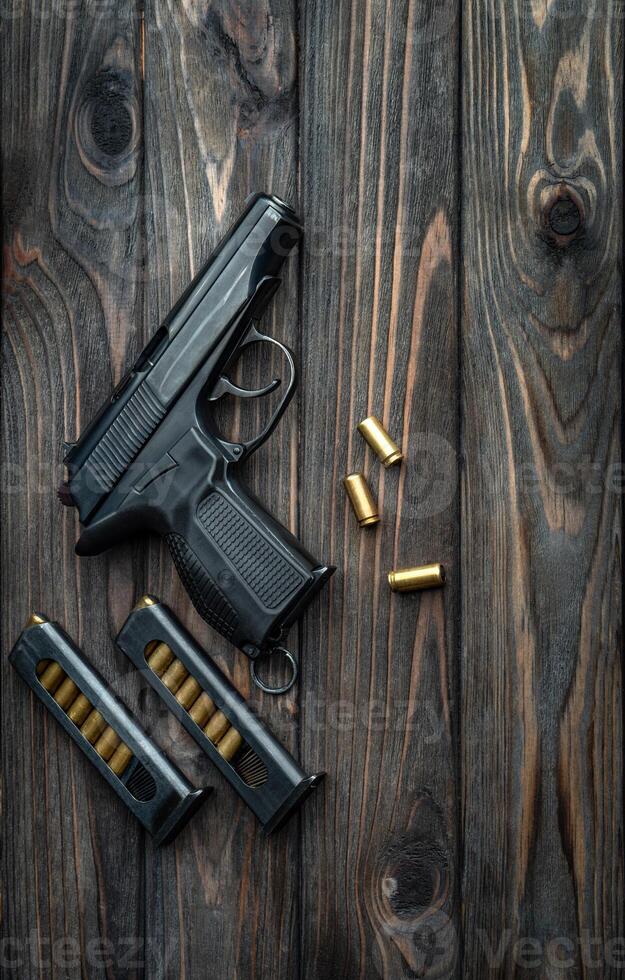 Pistol and cartridges for it on a wooden back. A short-barreled weapon for self-defense. photo