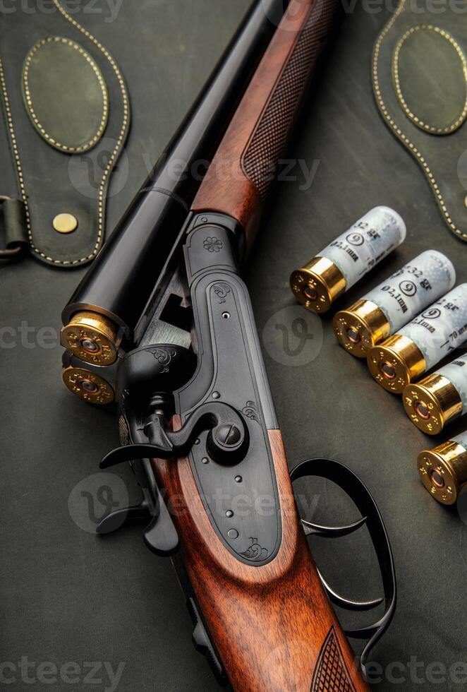 Classic trigger double-barreled hunting rifle on a green background. Smooth-bore hunting rifle open for reloading. Concept postcards for hunters. photo