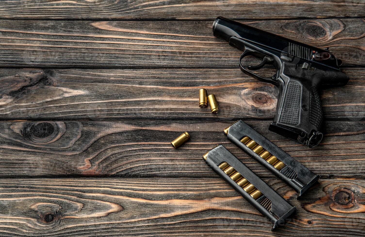 Pistol and cartridges for it on a wooden background. A short-barreled weapon for self-defense photo