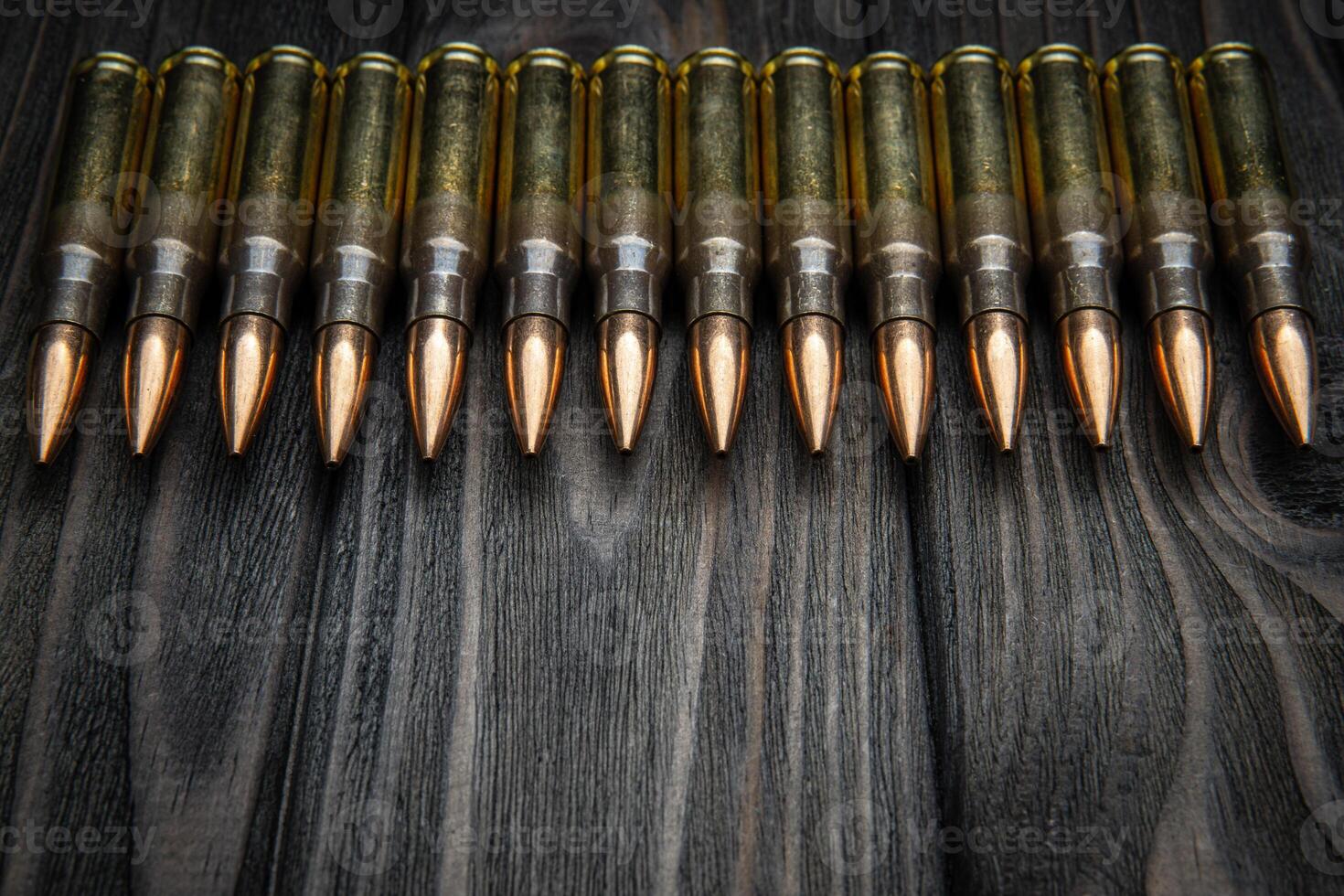 Cartridges for a carbine on a wooden surface. Weapon ammunition on a vintage table. Dark back. photo