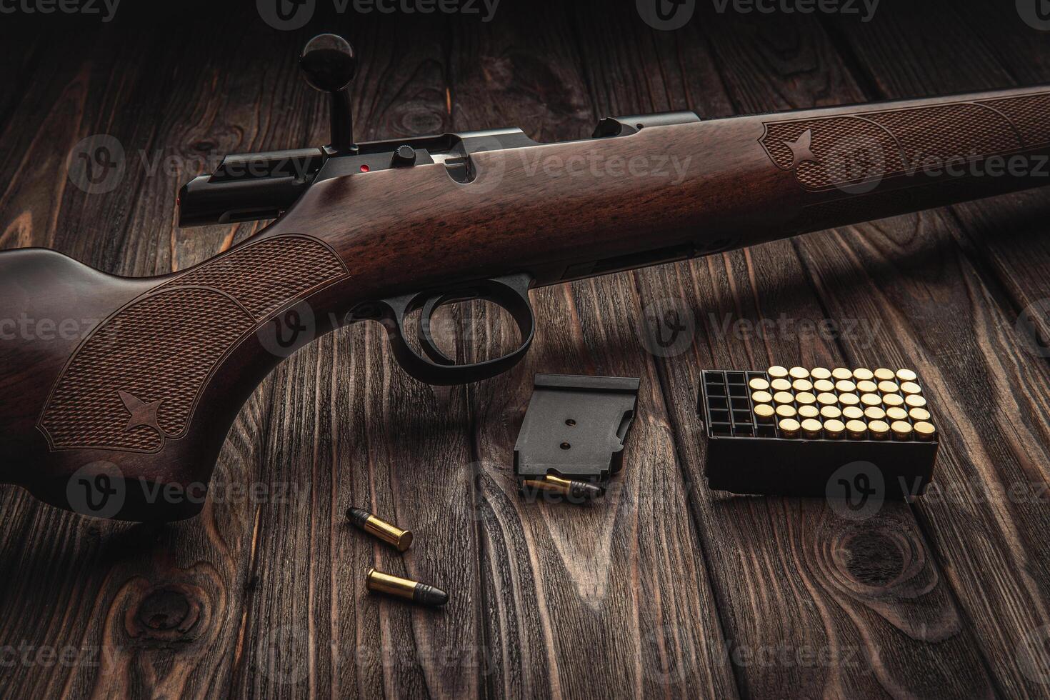 Classic bolt carbine .22lr with a wooden butt on a dark wooden surface. Weapons and cartridges for him on a wooden table. photo